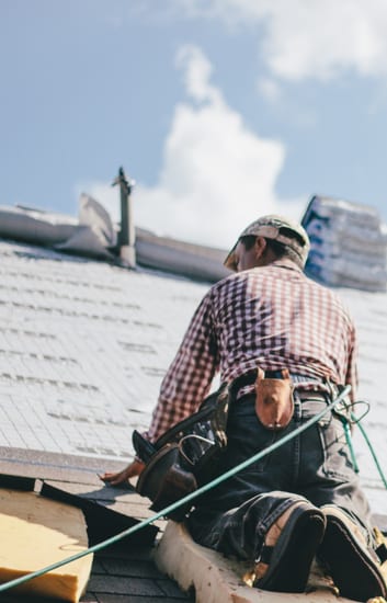 Roofer working a shingle roof on a harness