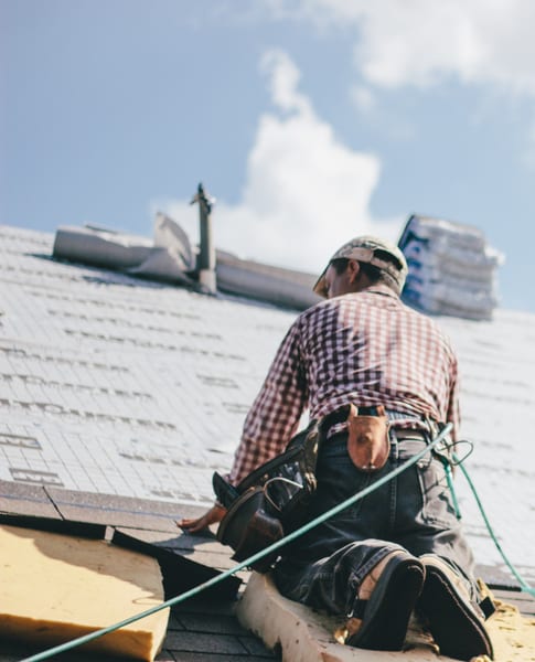 Roped roofer laying underlayment