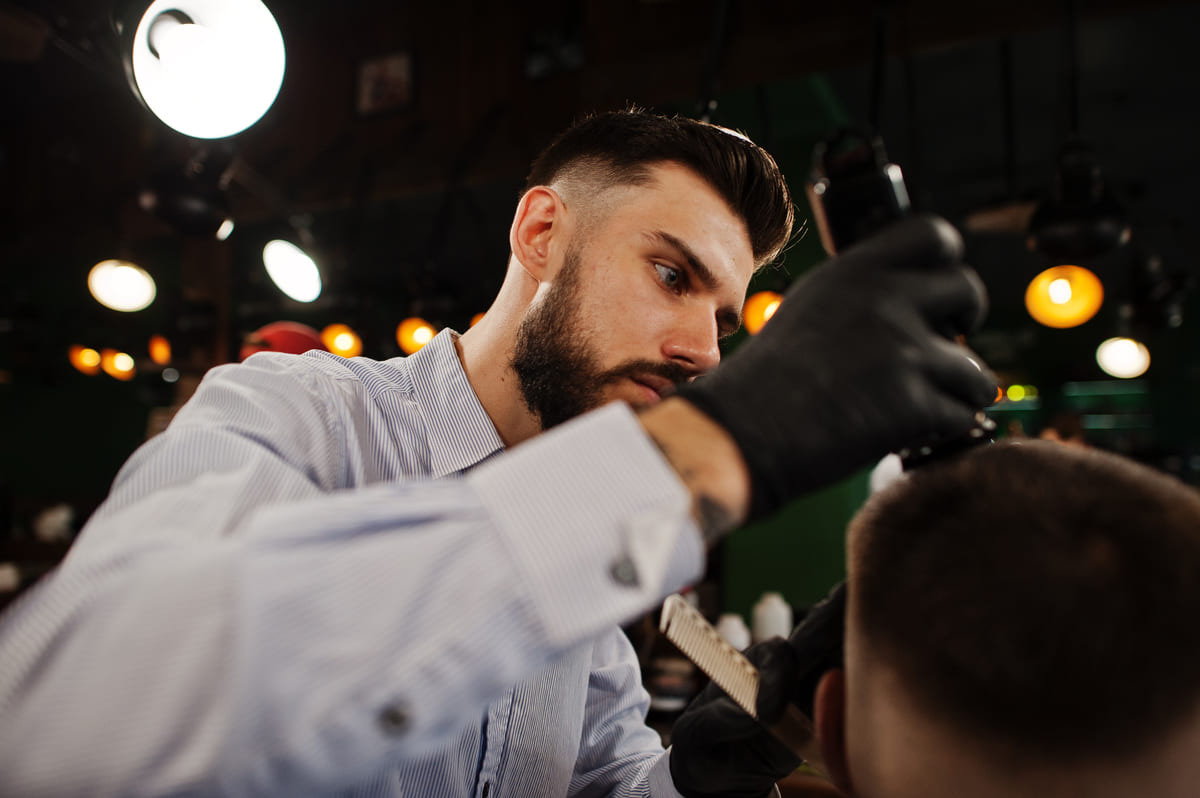 John working a clipper fade at the green wall