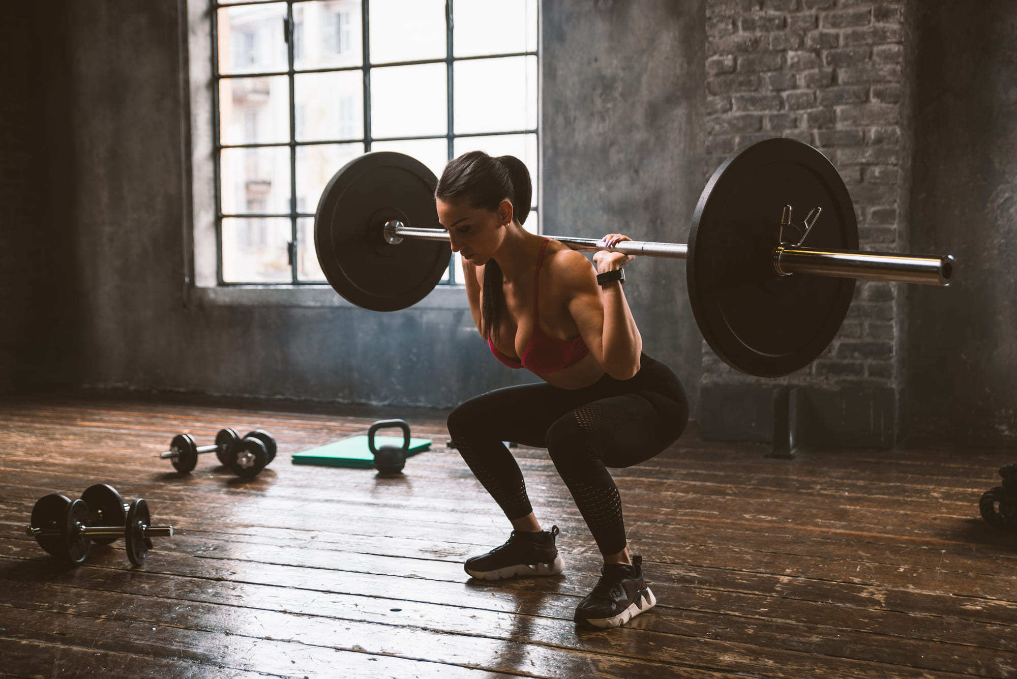 A lifter under a loaded barbell in the squat rack at Forge Athletic Club