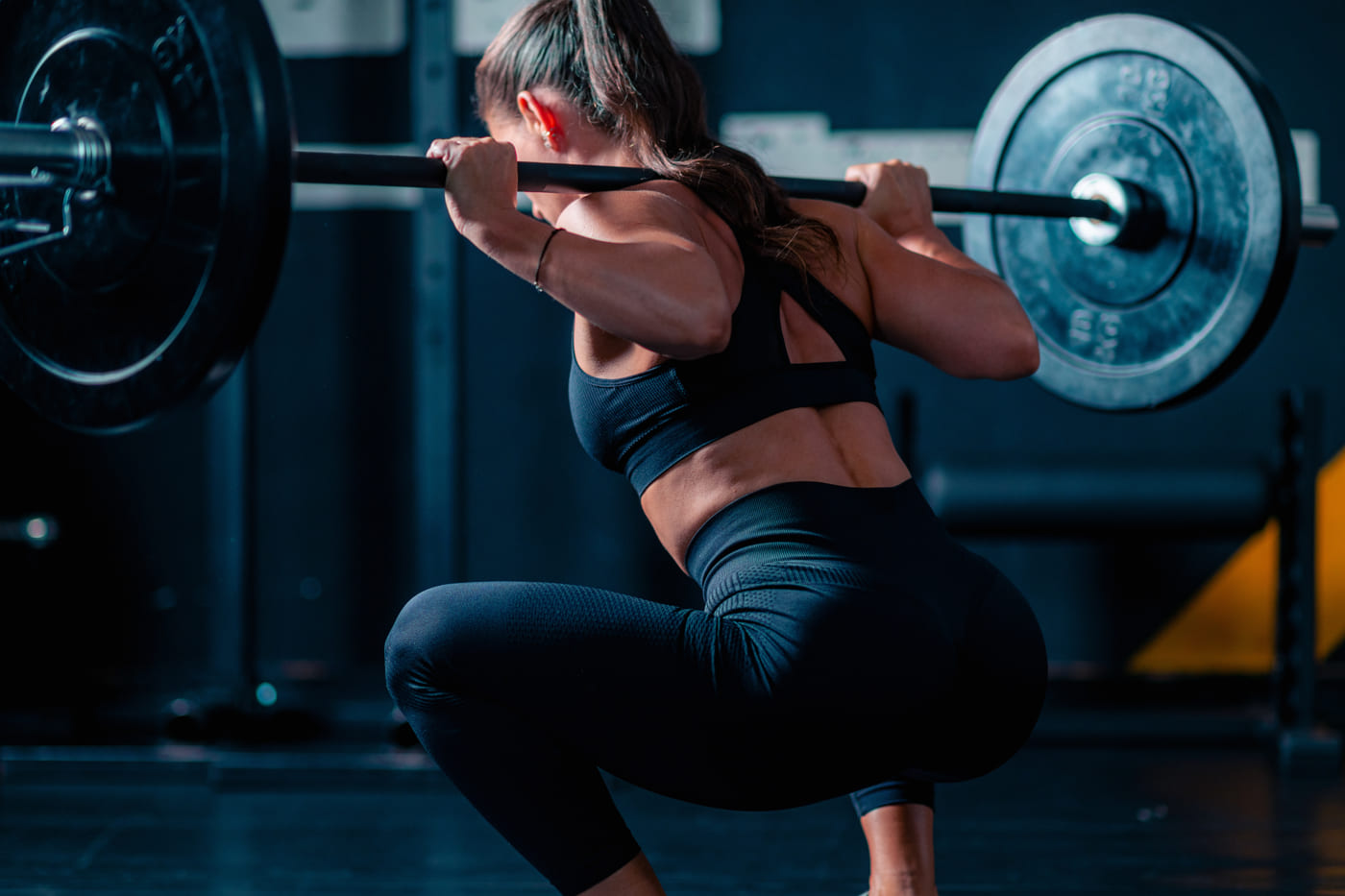 A member setting up for a back squat under coaching