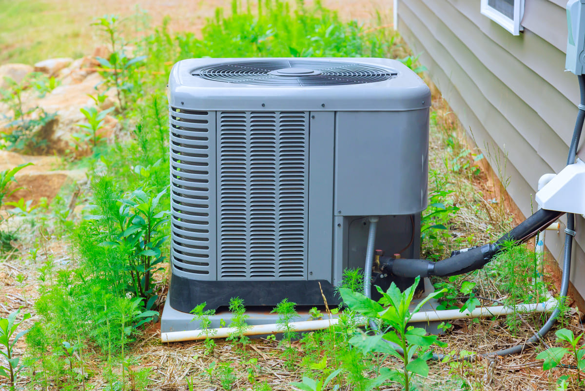A residential air conditioning condenser unit beside a house