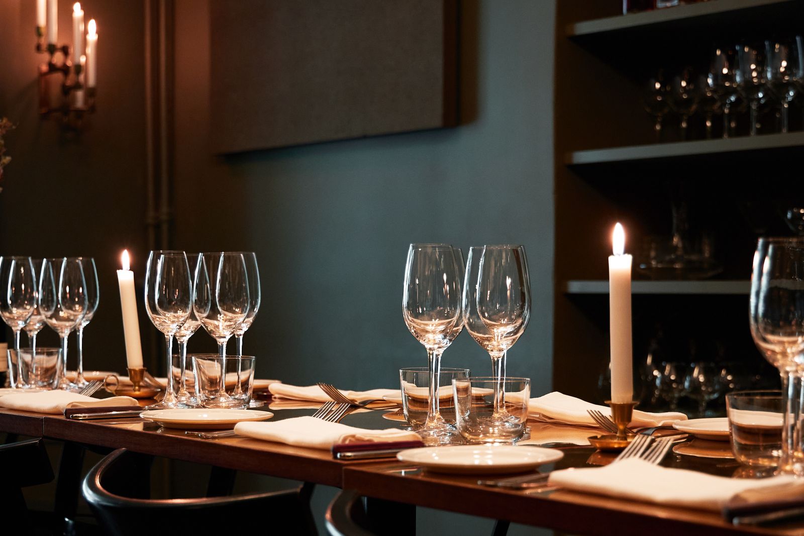 A long table set with wine glasses and lit candles in the private room