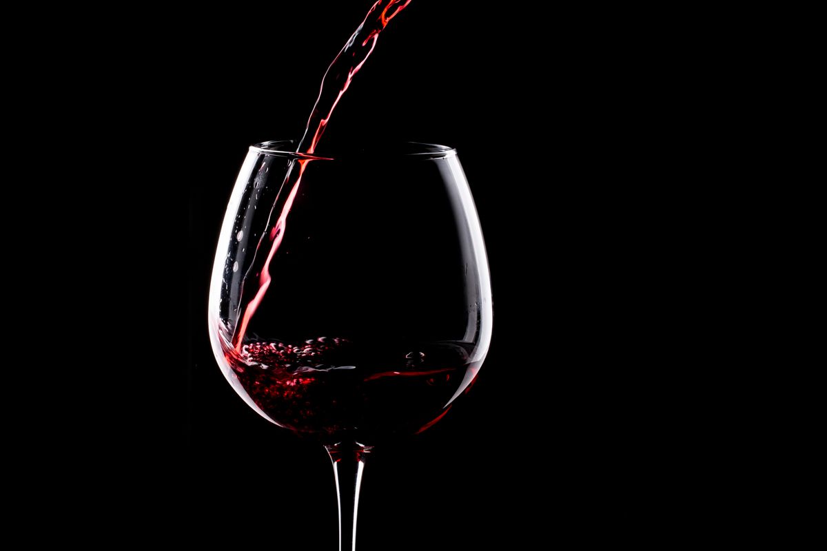 Red wine being poured into a glass against a dark background