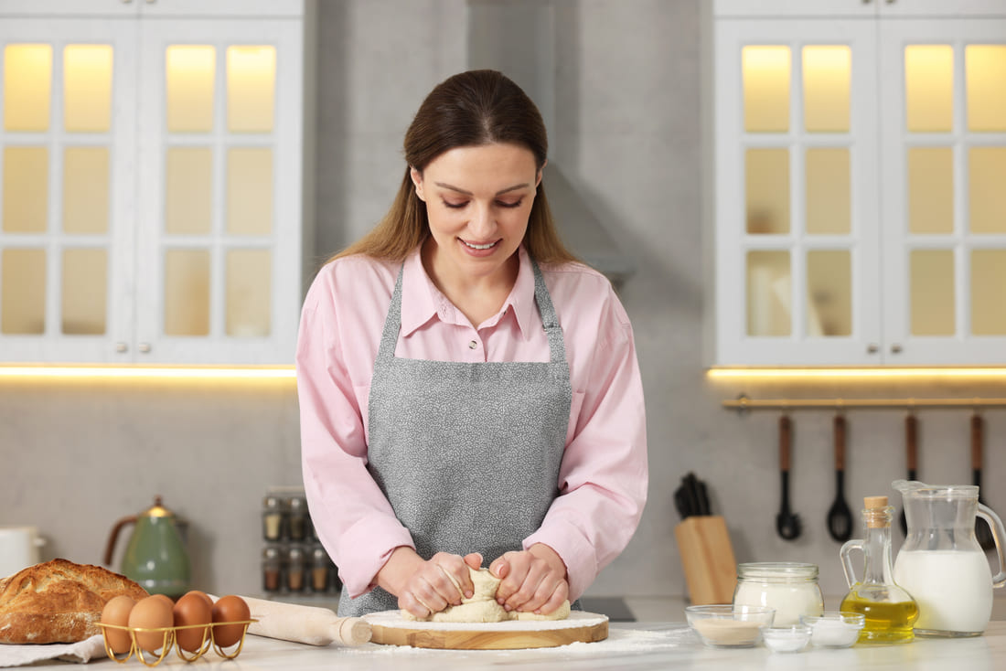 Sarah kneading bread dough by hand in her kitchen